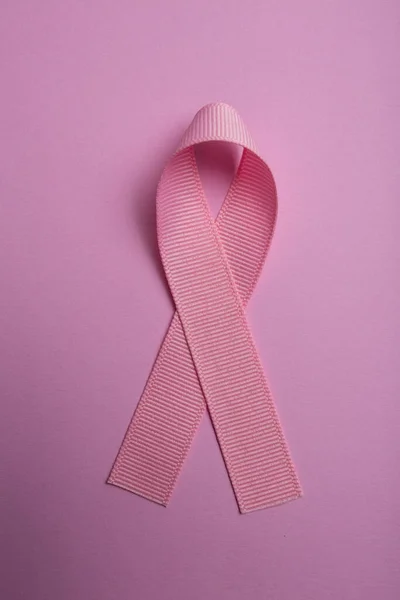 Pembe kurdele pembe arka planda izole edilmiş. Göğüs kanseri farkındalığının sembolü. Sağlık ve tıp konsepti. Önleyici önlemler. Kadın sağlığı