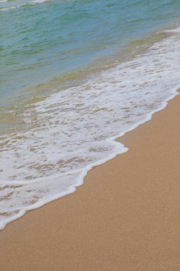 Plajda yumuşak dalgaların yakın çekimi. Merkezde seçici odak