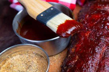 Kaburgaların üzerine barbekü sosu serpiştirilmiş fırça.