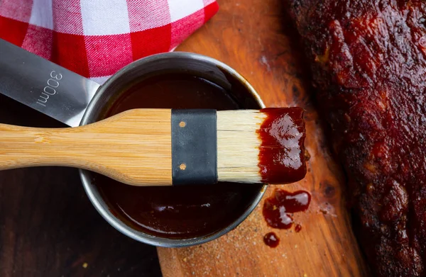 Kaburgaların üzerine barbekü sosu serpiştirilmiş fırça.