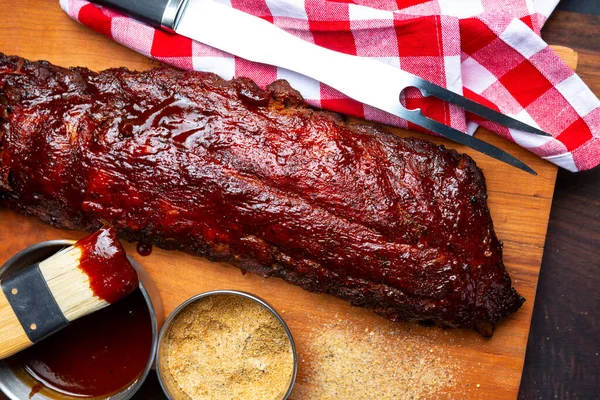 Soslu ve soslu eski bir kesme tahtasının üstünde ızgara domuz kaburgası ve sos.