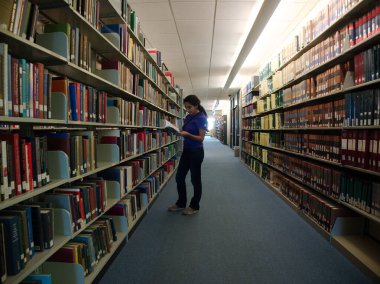 Baton Rouge, Louisiana, ABD - 2020: Bir öğrenci Louisiana Devlet Üniversitesi 'nin ana kütüphanesindeki Middleton Kütüphanesi' nde bir kitaba bakıyor.