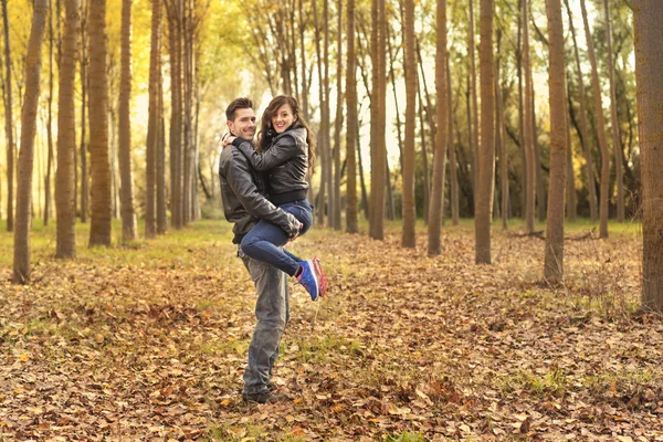 秋の公園でウォーキングのジーンズを着てロマンチックなカップル — ストック写真