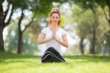 Parkta yoga egzersizi yapan güzel bir kadın.