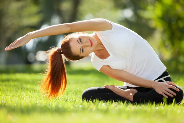 Mooie vrouw doet yoga oefeningen in het park — Stockfoto