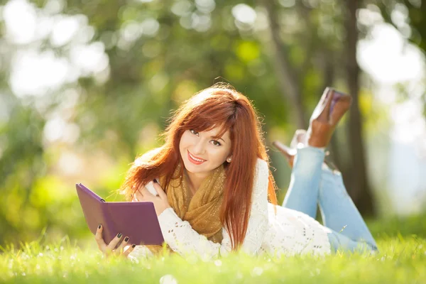 Jonge mooie vrouw met tablet in het park — Stockfoto