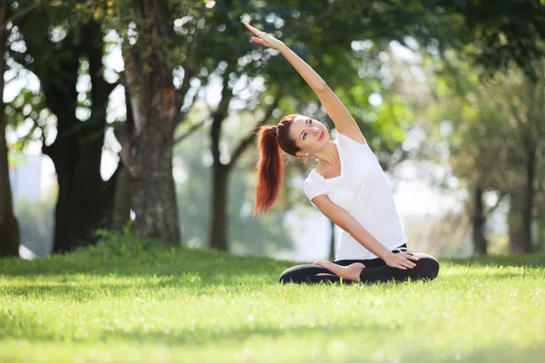 Parkta yoga egzersizi yapan güzel bir kadın. — Stok fotoğraf