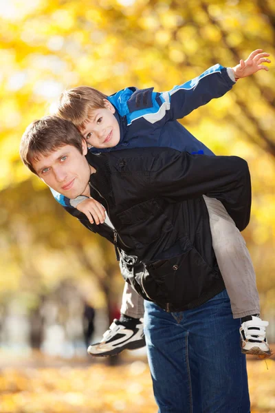 Gelukkig vader en zijn zoon in de herfst park — Stockfoto