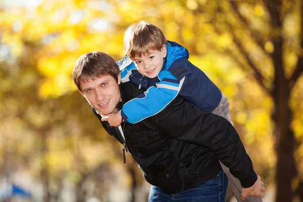 Счастливый отец и его сын в осеннем парке — стоковое фото