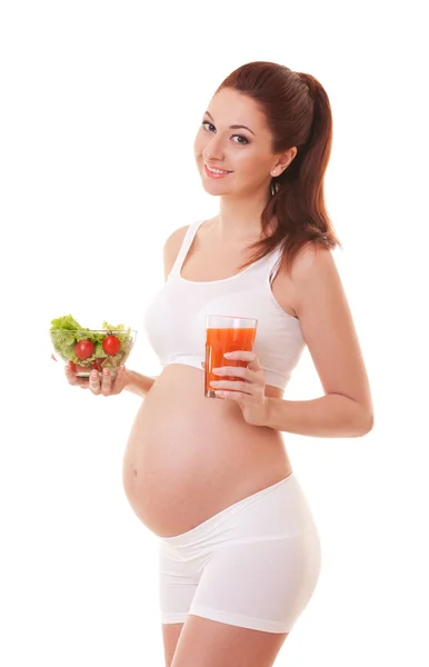 Mujer embarazada joven sosteniendo ensalada y vaso con jugo aislado sobre fondo blanco. Nutrición y dieta durante el embarazo . — Foto de Stock