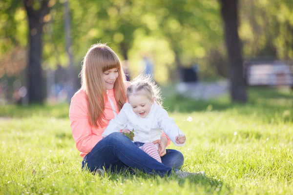 Parktaki mutlu anne ve kız. Aile hayatı olan güzel doğa manzarası. Mutlu bir aile yeşil çimlerin üzerinde birlikte dinleniyor, dışarıda eğleniyor. Aile hayatında mutluluk ve uyum.. — Stok fotoğraf