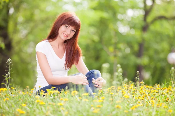 Carina donna riposo nel parco con fiori — Foto Stock