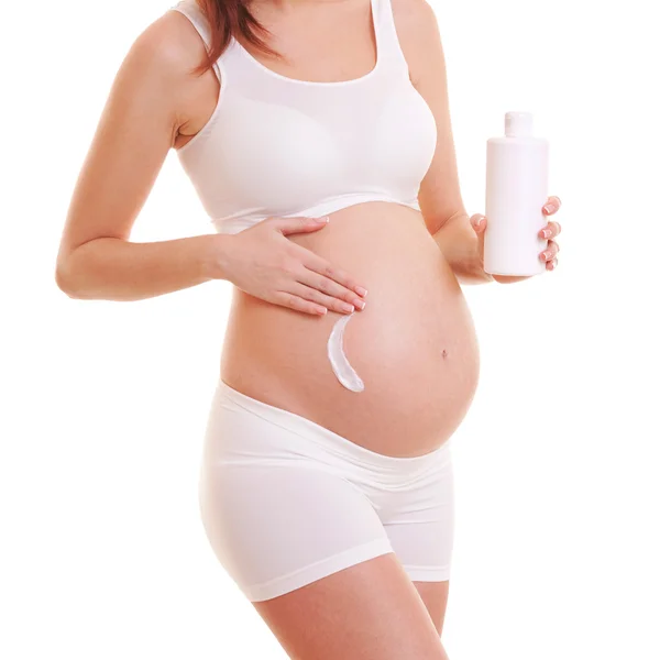 Mujer embarazada que aplica crema en su cuerpo. Aislado sobre blanco — Foto de Stock