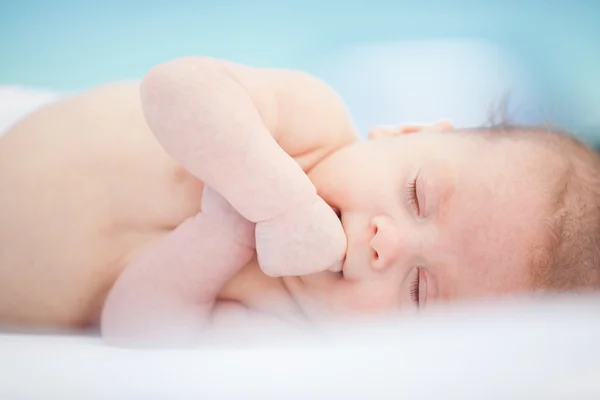 Маленький сонный малыш лежит на белой кровати — стоковое фото