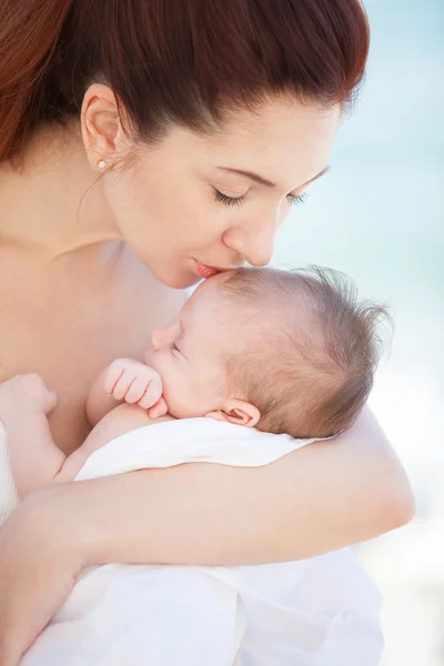 Glückliche Mutter küsst ihr süßes schlafendes Baby. Mutterschaft und Kinder-Konzept — Stockfoto