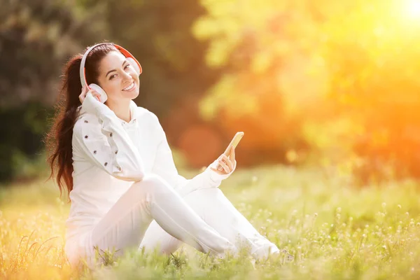快乐的女人带着耳机在秋天的公园里放松 美丽的自然景观 背景五彩斑斓 时尚界的女性喜欢秋天的手机里的音乐 户外生活方式 — 图库照片