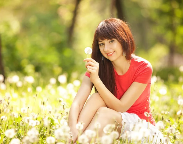 Cute woman in the park with dandelions — Zdjęcie stockowe