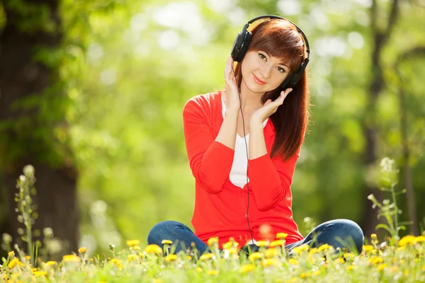 Gelukkige vrouw met hoofdtelefoon ontspannen in het park — Stockfoto