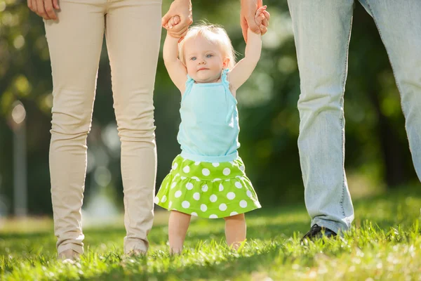 Mamma, pappa och dotter i parken. Första stegen — Stockfoto