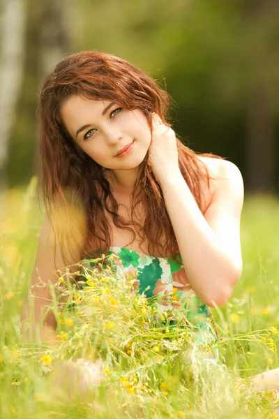 Jeune rousse femme dans le parc avec des fleurs — Photo