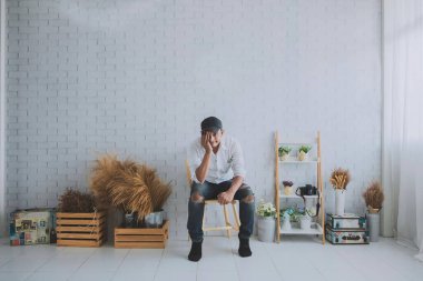 Çekici bir adam gülüyor ve gülümsüyor. Temiz beyaz bir odada, olumlu bir düşünce vardır..