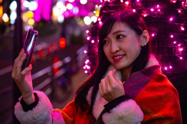 Japon bir kız, Shibuya 'nın aydınlık caddesinde gece selfie çekiyor.