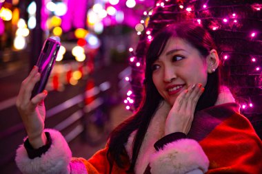 Japon bir kız, Shibuya 'nın aydınlık caddesinde gece selfie çekiyor.