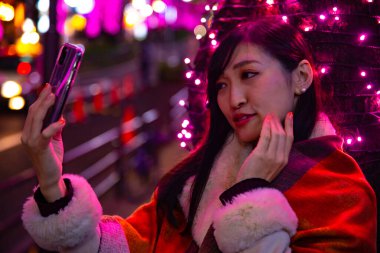 Japon bir kız, Shibuya 'nın aydınlık caddesinde gece selfie çekiyor.