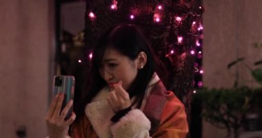 Japon bir kız, Shibuya 'nın aydınlık caddesinde gece selfie çekiyor.