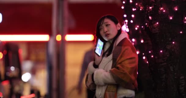 渋谷のライトアップされた夜の街で電話をかける日本人の女の子 — ストック動画