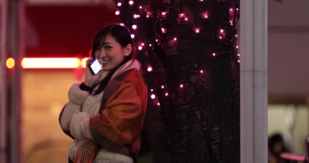 Japonská dívka volá telefon v noci osvětlené ulici v Shibuya — Stock video