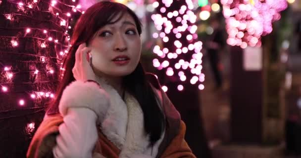 Japonská dívka volá telefon v noci osvětlené ulici v Shibuya handheld — Stock video