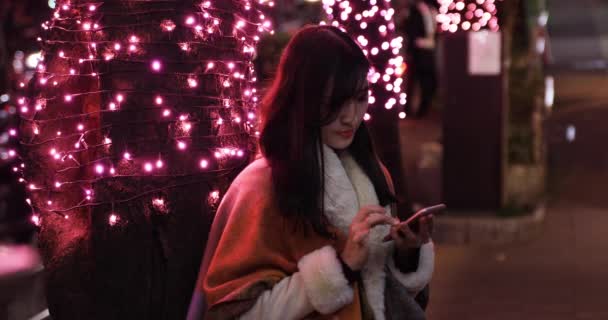 Seorang gadis Jepang mengirim pesan di malam hari diterangi jalan di dekat Shibuya ditembak — Stok Video