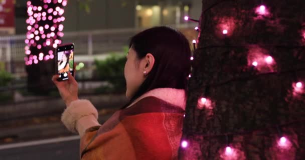 Una chica japonesa disparando selfie en la noche iluminado calle en Shibuya tiro de cerca — Vídeo de stock