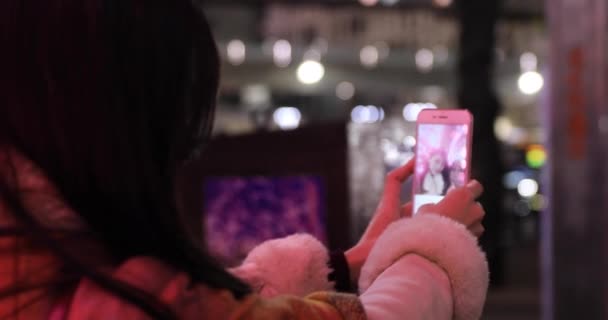 一名日本女孩在夜光中自拍，紧紧抓住石布亚的一条灯火通明的街道 — 图库视频影像