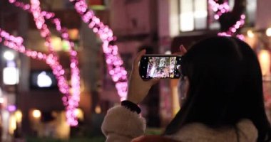 Shibuya 'nın gece sokağında el kamerasıyla ateş eden Japon bir kız.