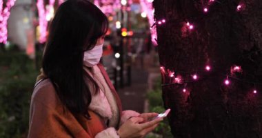 Maskeli bir Japon kız Shibuya 'daki gece sokağında ateş ediyor.