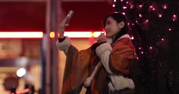 Japonská dívka střílí selfie v noci osvětlené ulici v Shibuya — Stock video