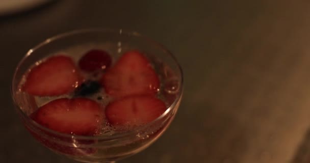 Um morango no champanhe na festa à noite handheld closeup — Vídeo de Stock