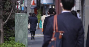 Shinjuku 'daki şehir merkezinde yüksek hızlı yürüyen ofis çalışanları.