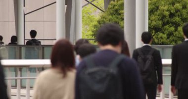 Shinagawa kentindeki ofis çalışanlarının ağır çekimde yürümesi.