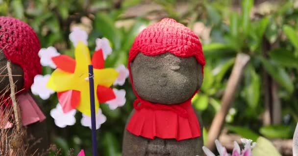 A slow motion of moving colorful windmills with Jizo statue daytime closeup — Stock Video