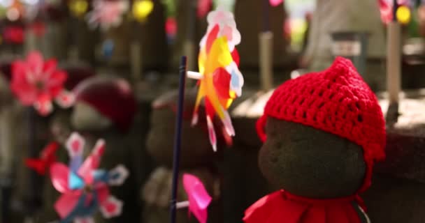 Un lent mouvement de moulins à vent colorés en mouvement avec statue Jizo en gros plan de jour — Video