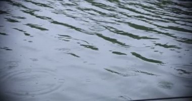 Yağmurlu bir günde suya yavaş bir yağmur damlası düşer.