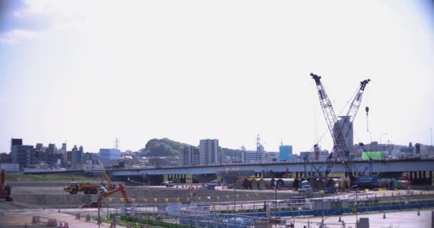 Grúas en movimiento en la construcción de tiro ancho diurno — Vídeo de stock