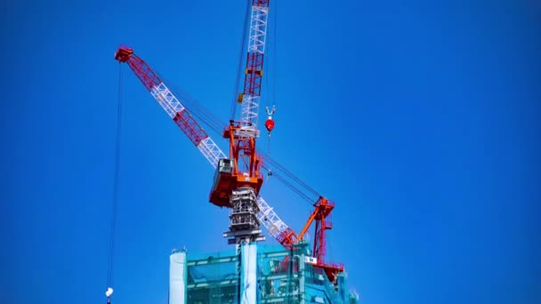 Un lapso de tiempo de la grúa de ida y vuelta detrás del cielo azul en la construcción en Tokio zoom — Vídeo de stock