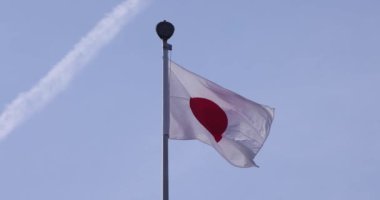 Mavi gökyüzünün arkasında Japon bayrağının yavaş bir hareketi