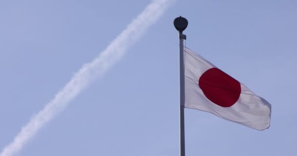 Una cámara lenta de bandera japonesa detrás del cielo azul — Vídeo de stock