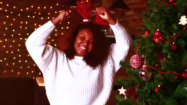 Spanyol boldog nő fehér pulóverben és szarvas szarvas kürt tánc és éneklés a nappaliban egyedül elszigeteltség karanténban otthon corona vírus kitörése — Stock videók