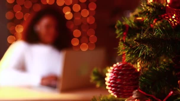 Afro femme shopping en ligne sur ordinateur portable dans intérieur confortable de noël. Préparation à Noël, le lobbying sur les ventes d'hiver — Video